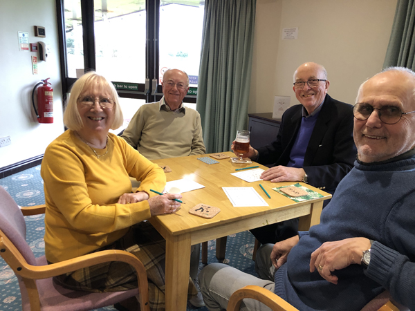 Margie, Geoff, Alan & Bill at their table, looking the camera and smiling.