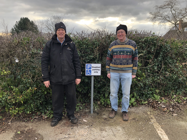 Ian and Geoff standing either side of the newly installed Disabled Parking sign.