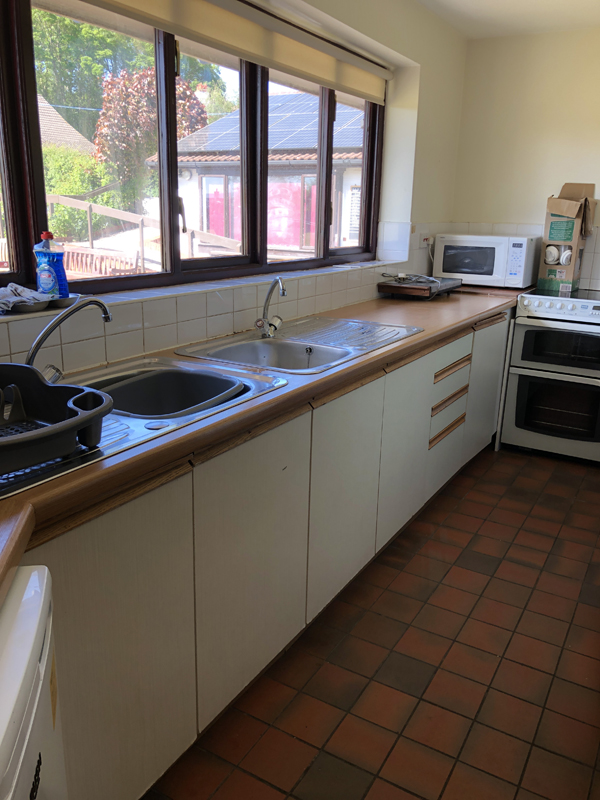 Picture of the kitchen all tidy with nothing on the windowsills or countertops. Looking from the entrance.