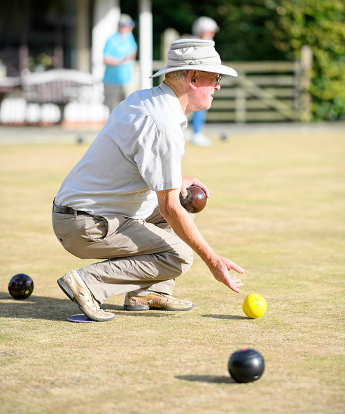 Man bending down to bowl the jack.