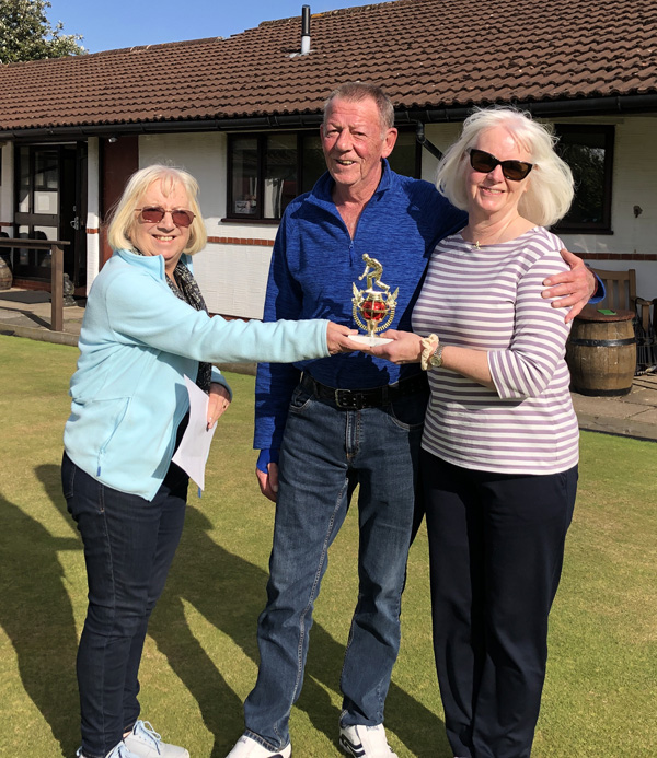 A woman presenting the weekend trophy to a man and a woman.