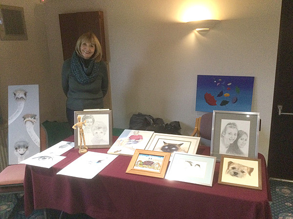 Laura standing behind a table displaying her paintings.