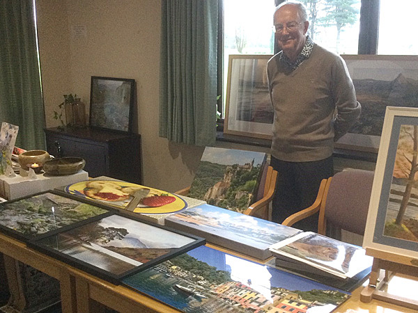 Geoff standing behind a table displaying his photographs.
