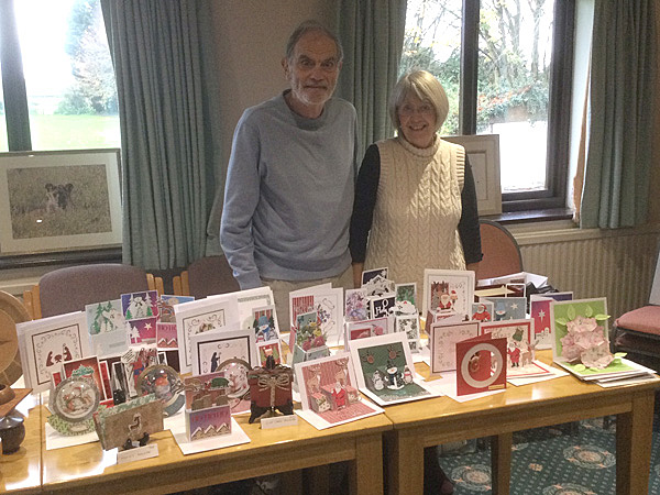 Kath & Rod standing behind a table displaying her handmade cards.
