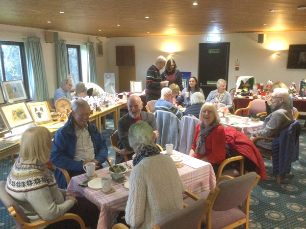 Attendees sitting at tables with coffee and cake.