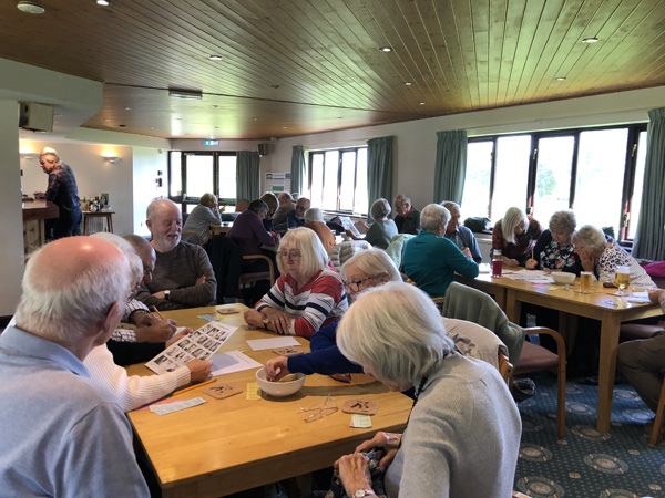 Bowls Club members sitting at tables in the Clubhouse intent on solving the table rounds.