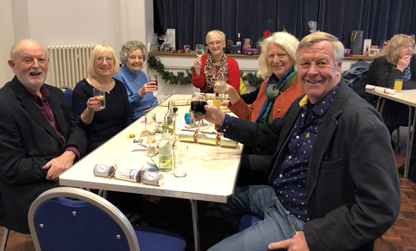 Ken, Margie, Mary, Anne, Lindy and Howard sitting at a table and raising their glasses to the camera.