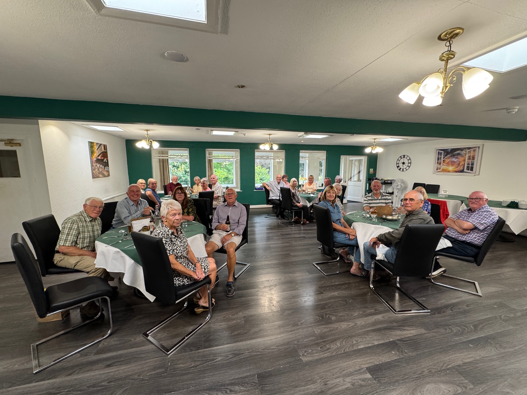 Panoramic shot of the dining room at Parkside. B&P members sitting at round tables looking at the camera.