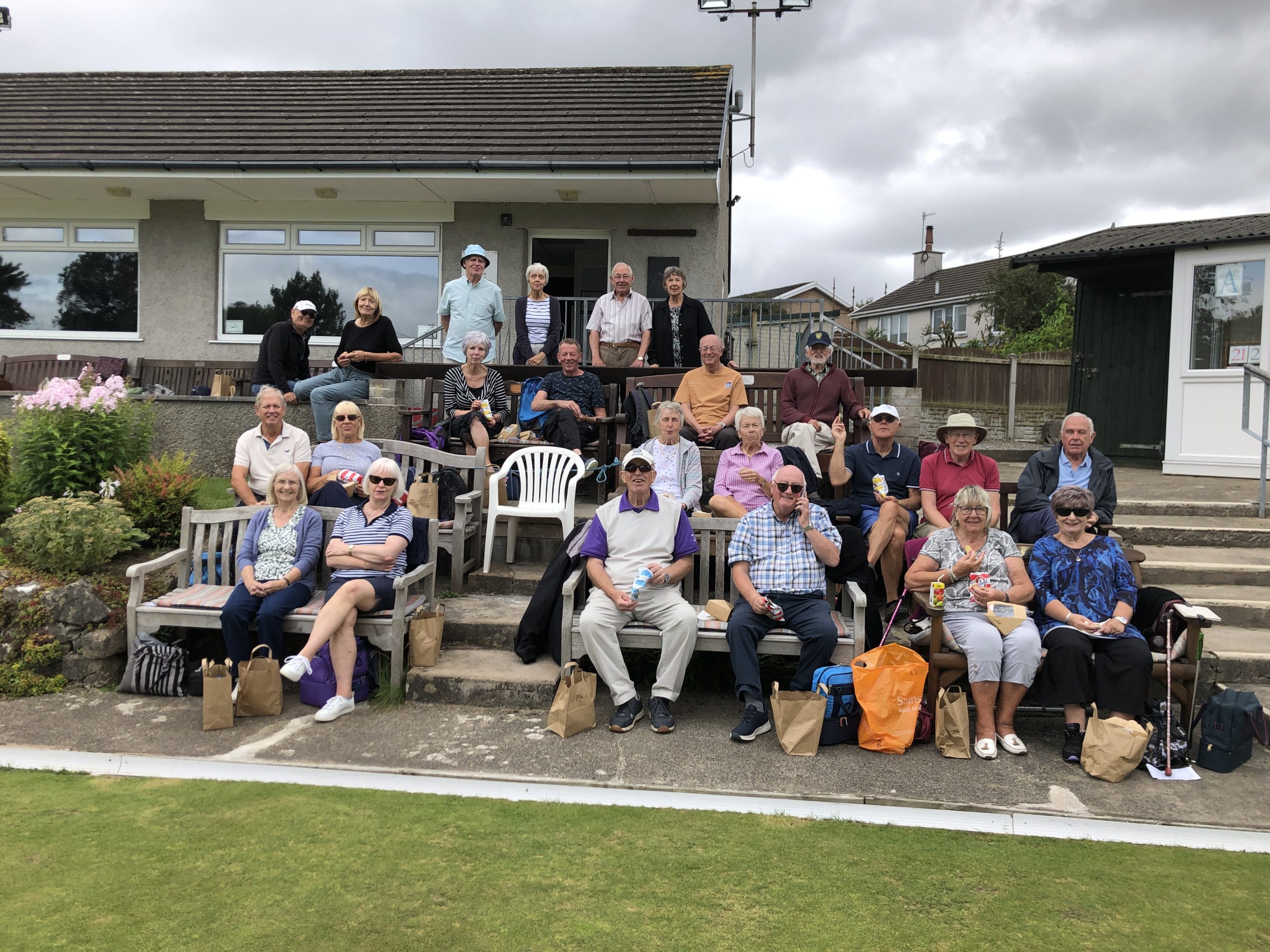 B&P Bowlers seated in rows at Arnside BC. They have just finished the social bowl and are eating lunch. The Chair and Secretary of Arnside BC are also in the picture