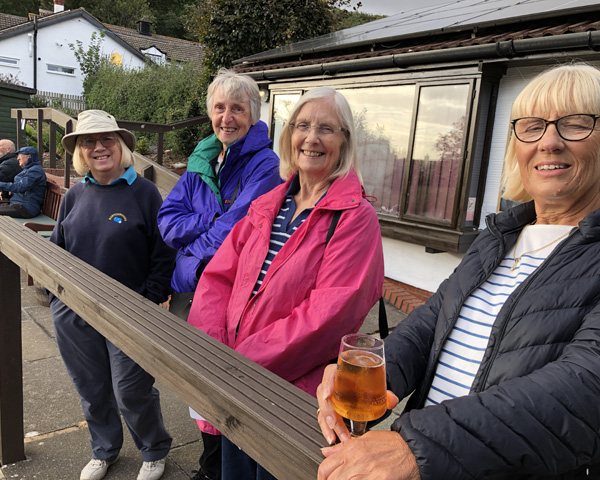 Four ladies from B&P standing at the railing and looking at the camera, smiling.