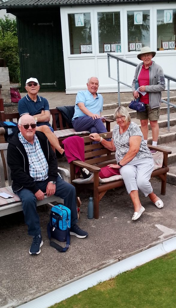 B&P members at Arnside Bowling Club, sitting on the tiered benches and standing on the steps.