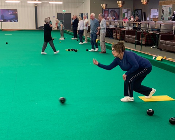 Bowlers on the mats at Prestatyn. In the foreground a woman has just delivered a bowl.