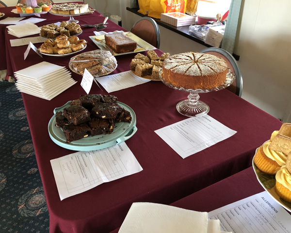 Table with cakes on plates and on cake stands.