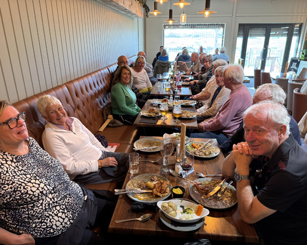 B&P and Neston bowlers sitting at the tables with food and drink,