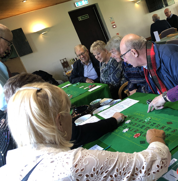 People at the Roulette table watching the spin and placing bets.