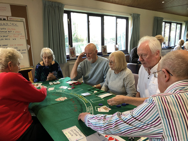 People at the Blackjack table as the dealer gives out more cards.