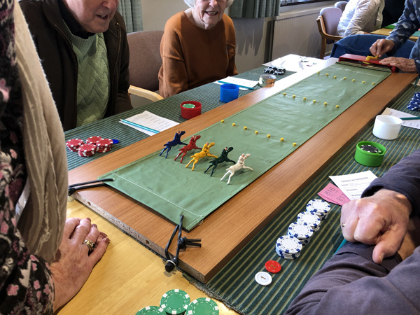 People sitting at table watching Escalado. The horses have just begun the race.