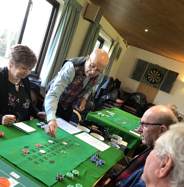 People gathered round the roulette table. The dealer is deciding who won the latest spin.