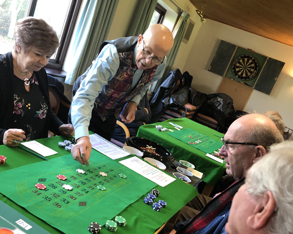 People gathered round the roulette table. The dealer is deciding who won the latest spin.