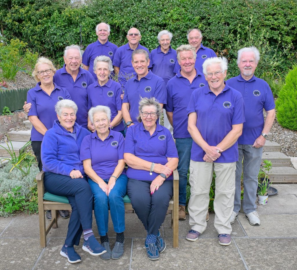 Members of the B&P Vets team (Division 4) at the green - three women sitting on a bench with two women and five men standing behind them. Four men in the back row.