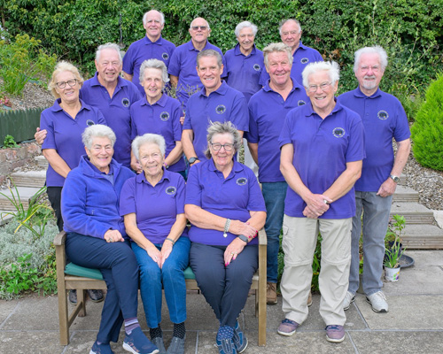 Members of the B&P Vets team (Division 4) at the green - three women sitting on a bench with two women and five men standing behind them. Four men in the back row.