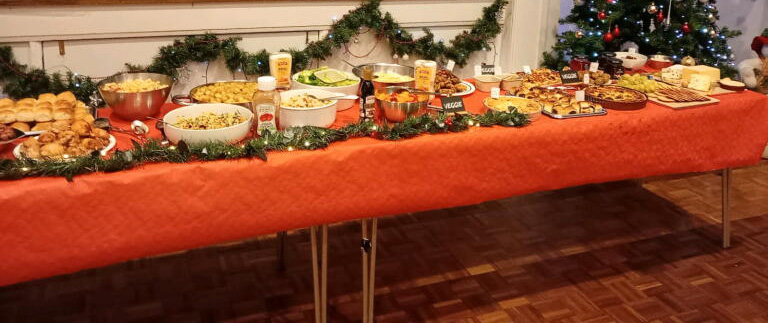 The food table, with red tablecloth and laden dishes.