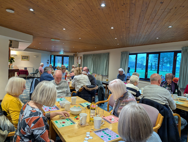 People sitting at tables in the Clubhouse playing bingo.