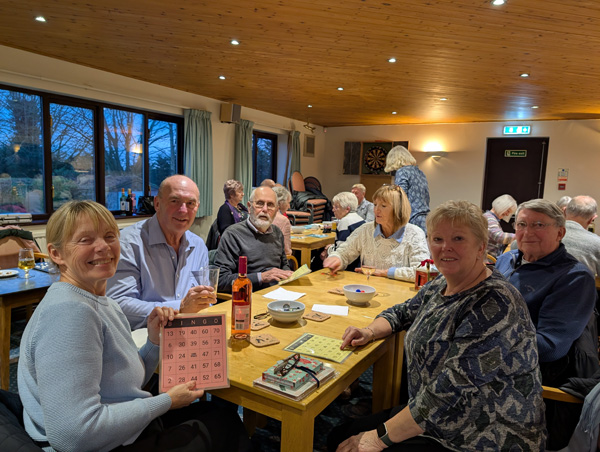 Members looking at the camera and holding up bingo cards.