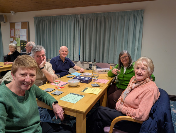 People sitting at table, smiling at the camera.