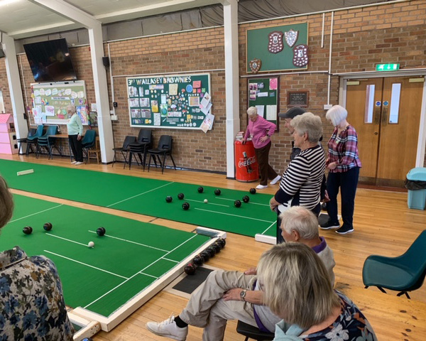 Bowlers standing at one end of the Hall aby two mats.