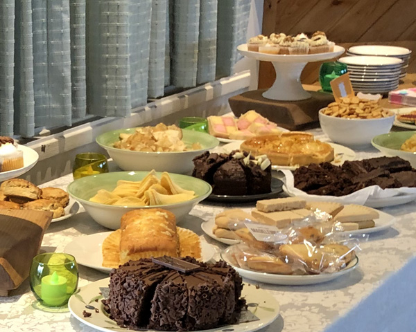 Table with plates of sandwiches, cakes, savouries.