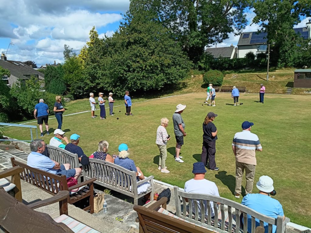 Bowlers on the green. Spectators watching from the sands.