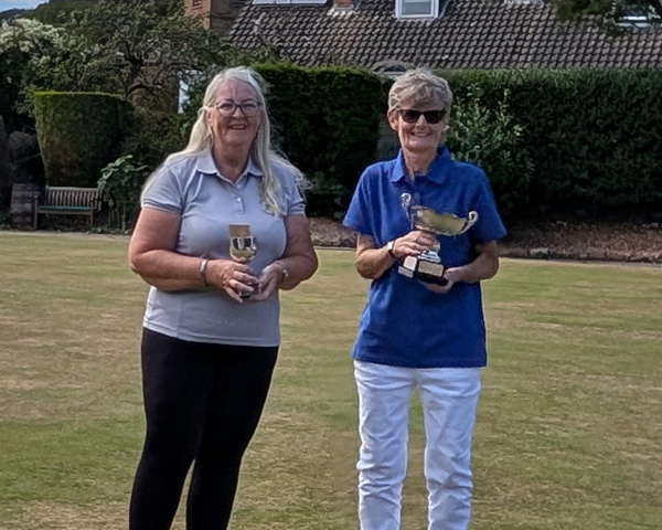 Two women on the green holding trophies