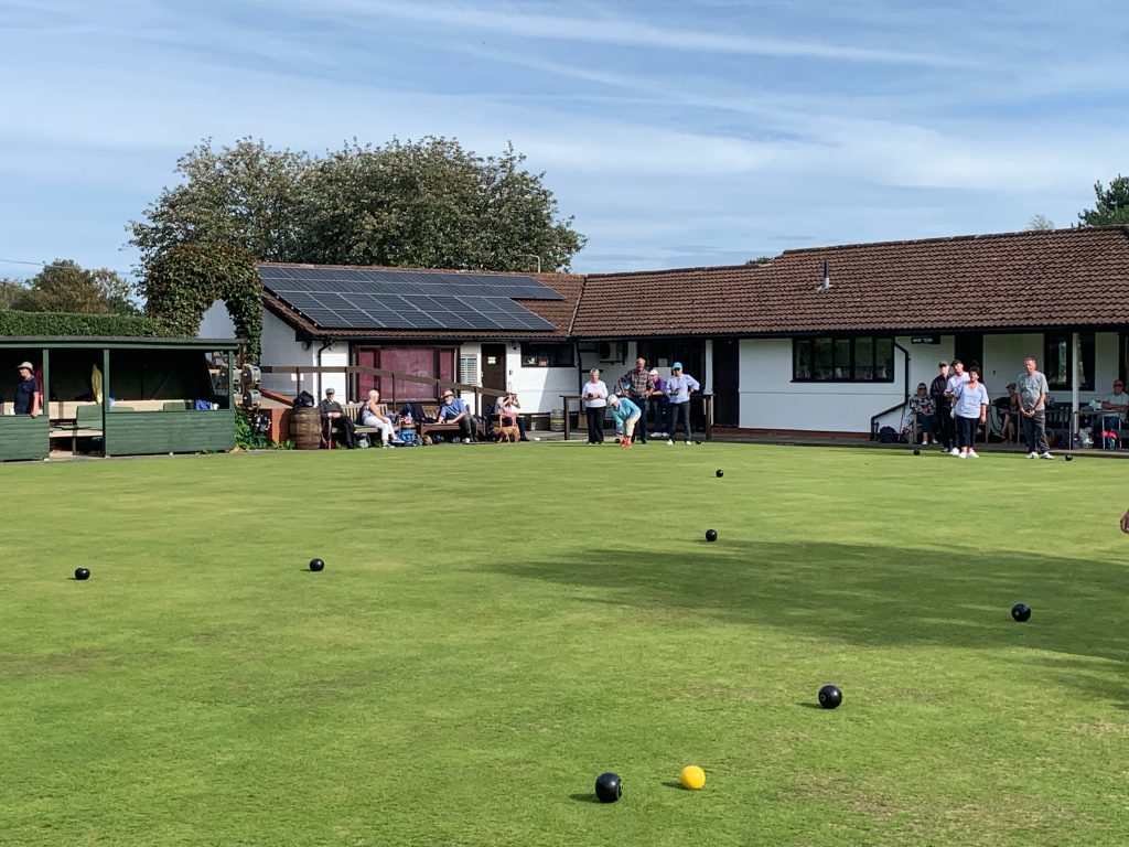 Bowlers on the green. Spectators in the background.